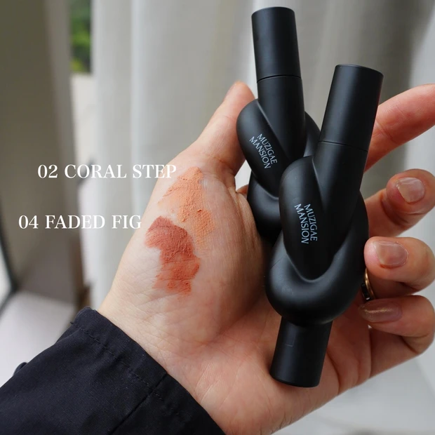 MUZIGAE MANSION（ムジゲマンション）のタイアップカバーティント2色（02 CORAL STEP・04 FADED FIG）のスウォッチを手の甲に塗り、2本を手に持った使用感写真。