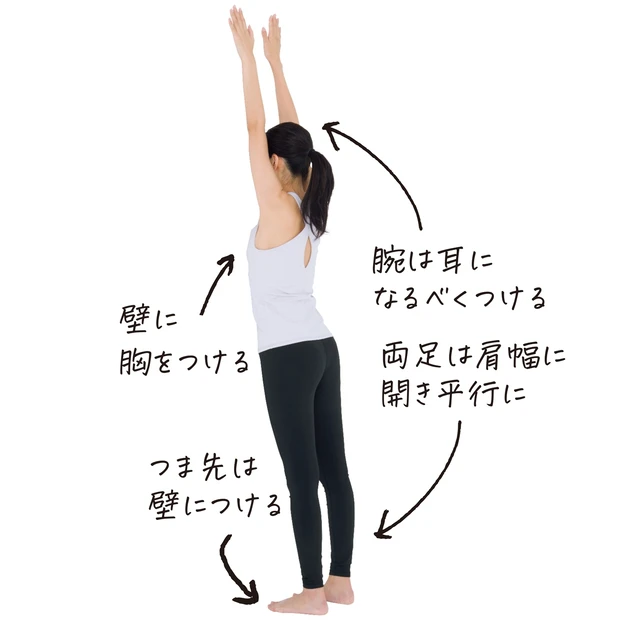 壁に胸をつけて立ち、両手を真上に伸ばす。足は肩幅に開き、つま先は壁につける。