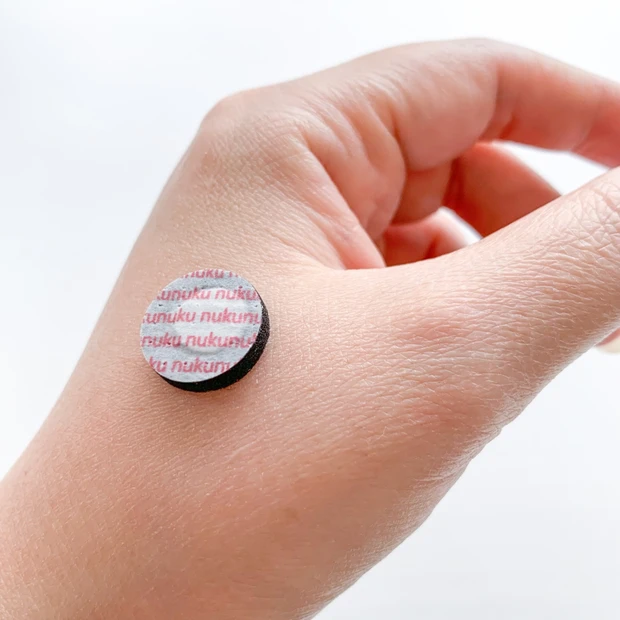 手のツボ（合谷など）に「火を使わないぬくぬく灸」を貼り付けて使用している様子