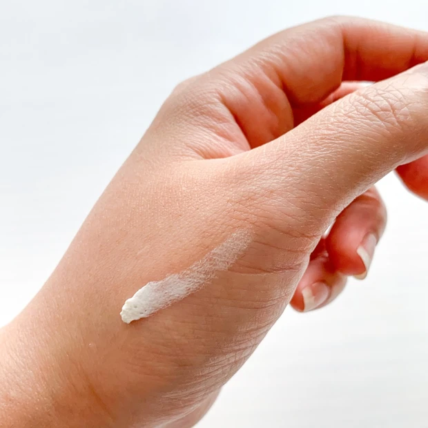 トータル V ラップの白いクリームを手の甲に乗せた写真。肌を引き締め、軽やかに整える洗い流すタイプのクリームマスク。