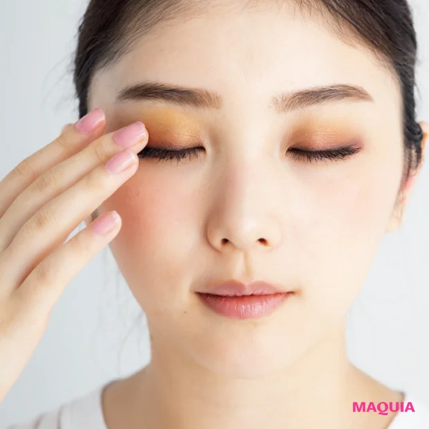 指先でまぶたのヨレを軽くなじませ、別の指先でゴールド系アイシャドウをワイパー塗りする。